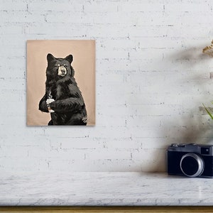 May include: A black bear holding a white coffee cup. The bear is standing on a light brown background.