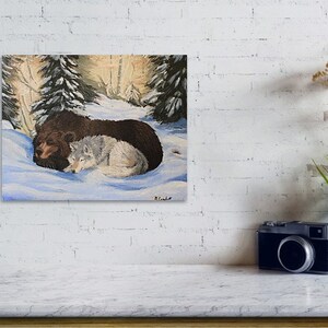 May include: A painting of a brown bear and a white wolf cuddling together in a snowy forest setting. The animals are lying on their sides with their heads touching. The background is a soft, muted palette of greens and browns, with a few trees visible.