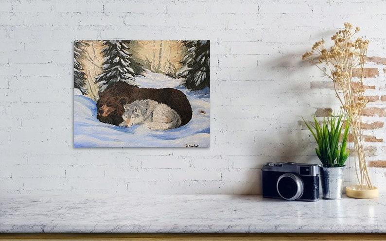 May include: A painting of a brown bear and a white wolf cuddling together in a snowy forest setting. The animals are lying on their sides with their heads touching. The background is a soft, muted palette of greens and browns, with a few trees visible.