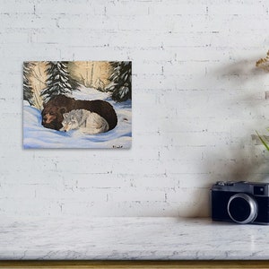 May include: A painting of a brown bear and a white wolf cuddling in a snowy forest setting. The bear is lying on its side with its head resting on the wolf's back. The wolf is curled up next to the bear, with its head resting on the bear's side. The forest is depicted in the background with trees and snow.