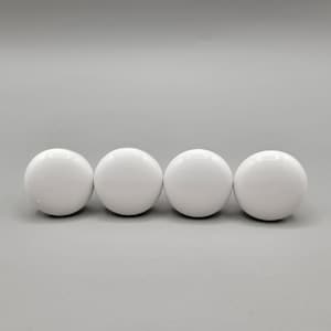May include: Four white ceramic knobs, each with a smooth, rounded surface.