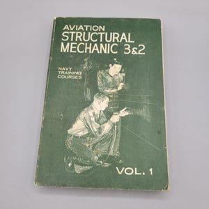 May include: A green book titled "Aviation Structural Mechanic 3&2" with the words "Navy Training Courses" and "Vol. 1" on the cover. The cover features a black and white illustration of two men working on an aircraft.