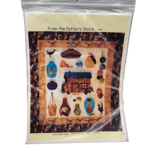 May include: A packaged craft kit featuring a quilt design with pottery-themed illustrations. The design includes a brown shack, various vases, and the text "From the Potter's Shack © 2004". The package is sealed in a clear plastic bag.