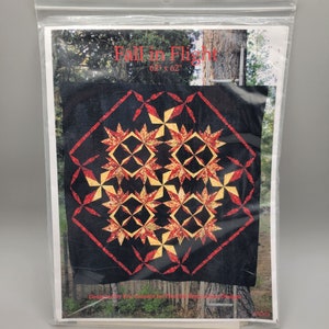 May include: A quilt pattern titled "Fall in Flight" with a black background and a design of red and gold stars. The quilt is 62 inches by 62 inches.