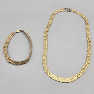 May include: A gold-tone necklace and bracelet set with a textured, woven chain design.