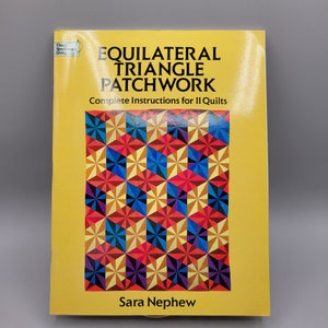 May include: A yellow book titled "Equilateral Triangle Patchwork" with a colorful quilt pattern on the cover. The book includes complete instructions for 11 quilts and is by Sara Nephew.
