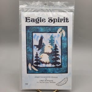 May include: A quilting pattern titled "Eagle Spirit" by Carol Robinson. The pattern features a silhouette of two eagles and a pine tree against a blue and white background. The pattern is from Sunset Silhouette Designs.