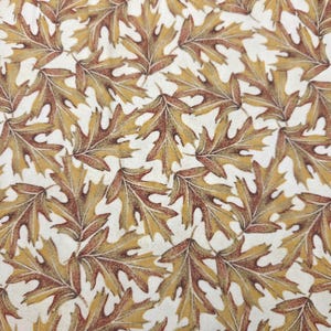 May include: A fabric pattern featuring a repeating print of oak leaves in shades of golden yellow, tan, and deep brown. The leaves are arranged in an overlapping, scattered orientation against a solid, off-white, cream-colored background.