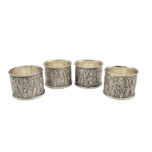 May include: Set of four silver napkin rings with a grapevine design.
