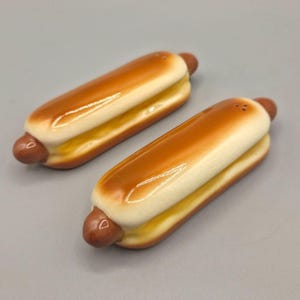 May include: A set of three ceramic mugs with a speckled, matte finish. The mugs are in shades of cream, light gray, and dark gray. Each mug has a simple, minimalist design and a rounded handle.