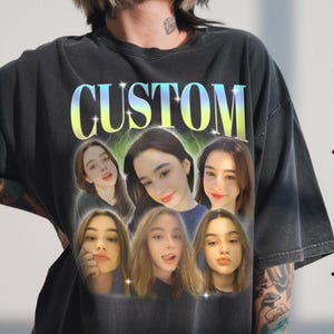 Puede incluir: Camiseta gris oscuro con la palabra "CUSTOM" en degradado amarillo y azul. La camiseta presenta un gráfico del rostro de una mujer repetido seis veces. El fondo tiene un diseño de rayo.