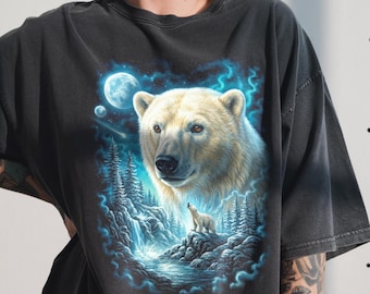 Può includere: T-shirt grigio scuro con un'illustrazione dettagliata di un orso polare e del suo cucciolo in un paesaggio innevato al chiaro di luna. Il design include una cascata, alberi e un cielo notturno con luna piena e stelle. Il pelo dell'orso è bianco.