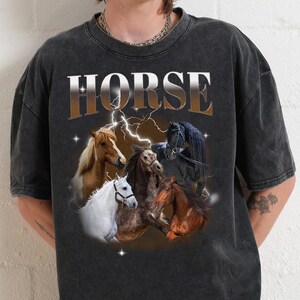 May include: A black t-shirt with a vintage-style graphic of horses and the word "HORSE" printed in large, bold letters. The graphic features five horses in various poses, including a black horse with a white stripe, a brown horse with a white mane, a white horse, a brown and white horse, and a brown horse with a white stripe.