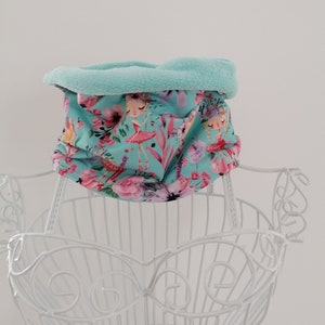 Könnte beinhalten: Ein hellblauer Halsschmuck mit einem Blumenmuster mit rosa Blüten und Feen. Der Halsschmuck ist mit einem weichen, hellblauen Fleece gefüttert.