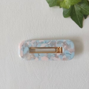 May include: A light blue and pink marbled hair clip with a gold metal spring.