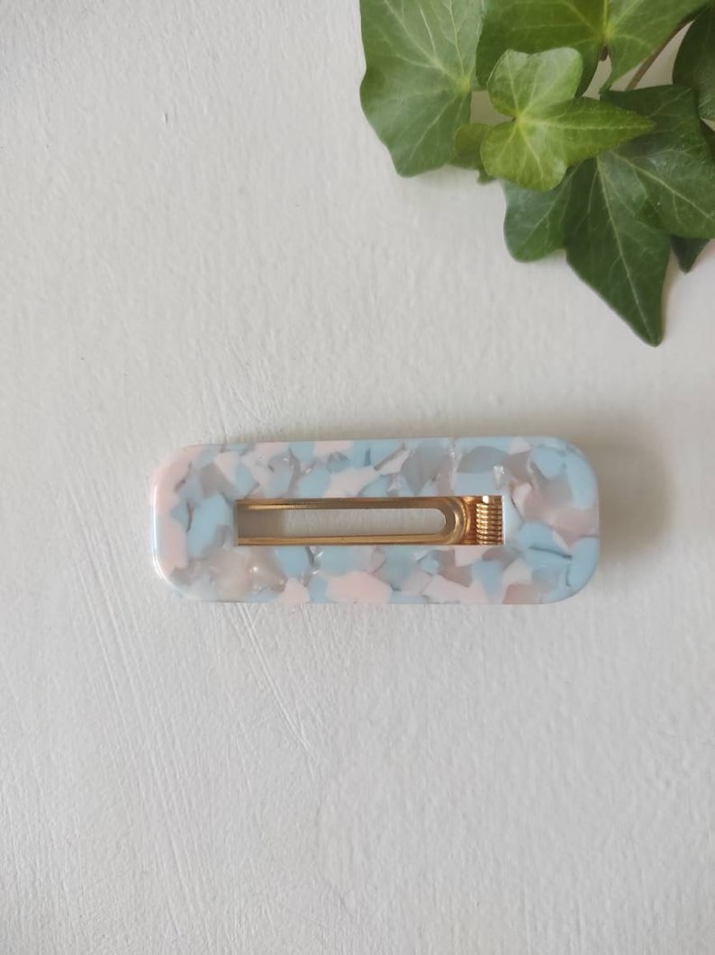 May include: A light blue and pink marbled hair clip with a gold metal spring.