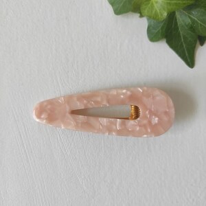 May include: A pink and white marbled hair clip with a gold metal spring.