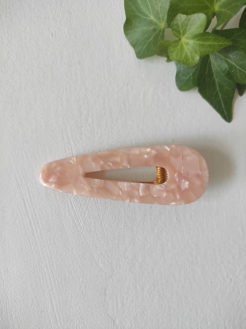May include: A pink and white marbled hair clip with a gold metal spring.