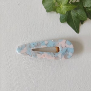 May include: A light blue and pink marbled hair clip with a gold spring.