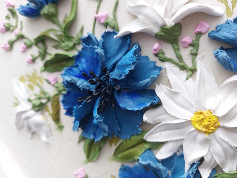 Puede incluir: Primer plano de una flor azul con p&eacute;talos blancos y un centro amarillo. La flor est&aacute; rodeada de hojas verdes y otras flores.