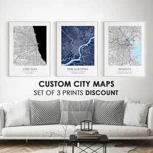 May include: Three framed city maps, one black and white, one blue, and one light blue, with the city names "Chicago", "Philadelphia", and "Boston" printed below each map. The text "CUSTOM CITY MAPS SET OF 3 PRINTS DISCOUNT" is printed below the maps.