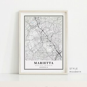 May include: Framed black and white map print of Marietta, Georgia, with street details and coordinates. The print is labeled "Marietta" and "Georgia" in a minimalist style, with the words "Style Modern" on the right side.