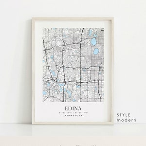 May include: A framed map print of Edina, Minnesota, featuring a detailed black and white street grid with light blue water features. The city name and coordinates are displayed at the bottom, with "STYLE modern" on the right. The frame is a light neutral color.