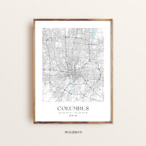 May include: A black and white map print of Columbus, Ohio with the city name and coordinates printed at the bottom. The map is framed in a light brown wood frame.