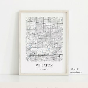 May include: Framed map print of Wheaton, Illinois, in a modern style. The black and white map details streets, parks, and waterways. The city name and coordinates are printed below the map. The frame is a light neutral color.