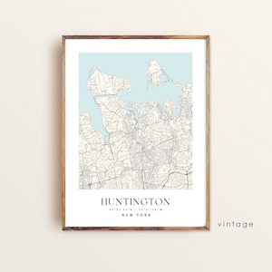 May include: A framed vintage map print of Huntington, New York, with a light blue background. The map features detailed street layouts and the town's name and coordinates in a minimalist design. The frame is made of wood.