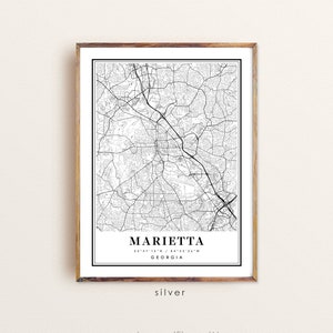 May include: A framed black and white map print of Marietta, Georgia, with the city name and coordinates displayed. The print is in a wooden frame and includes the word "silver" at the bottom.