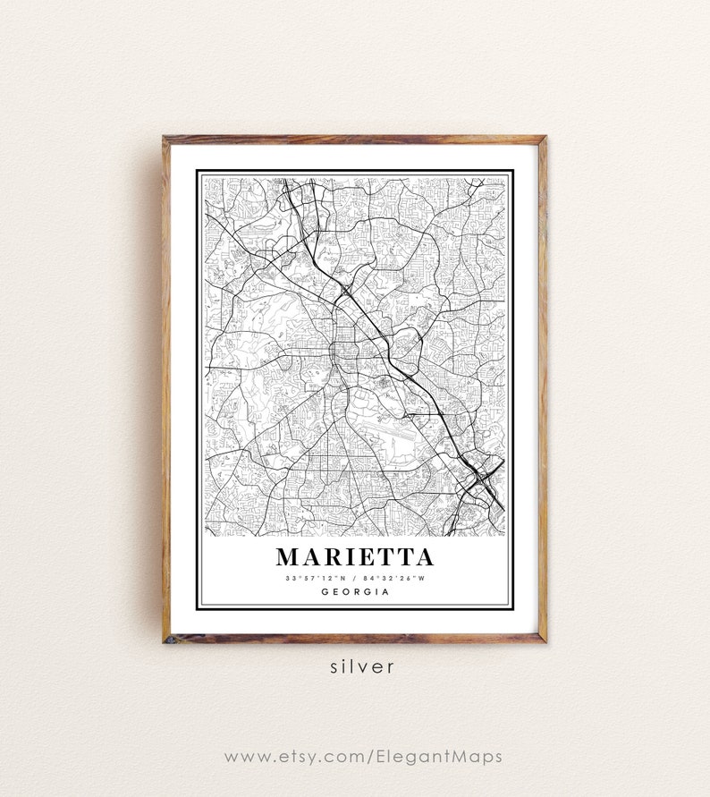 May include: A framed black and white map print of Marietta, Georgia, with the city name and coordinates displayed. The print is in a wooden frame and includes the word "silver" at the bottom.