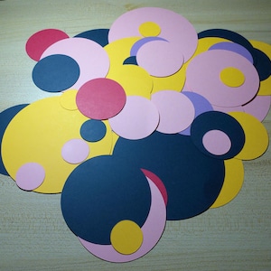 May include: An abstract art piece made of various sized circles in shades of pink, yellow, blue, and red. The circles are layered on top of each other to create a visually interesting design.