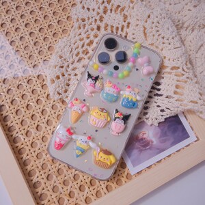 May include: A clear phone case with a colorful beaded charm and various cartoon character stickers. The case is decorated with glitter and hearts.