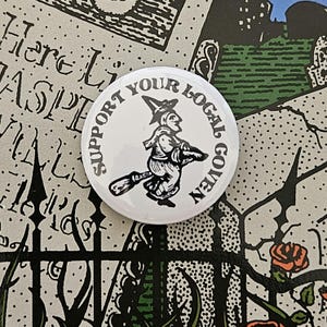 May include: White button with black text that reads "Support Your Local Coven" and a black and white illustration of a witch riding a broomstick.