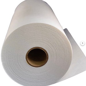 May include: A white roll of interfacing fabric, a type of fusible material used in sewing and quilting to stabilise and add structure to fabrics.