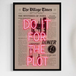 May include: A framed print of a vintage newspaper with the words "Do It For The Plot" in pink neon lettering. The print is hanging on a white wall above a zebra-print armchair and a potted plant.
