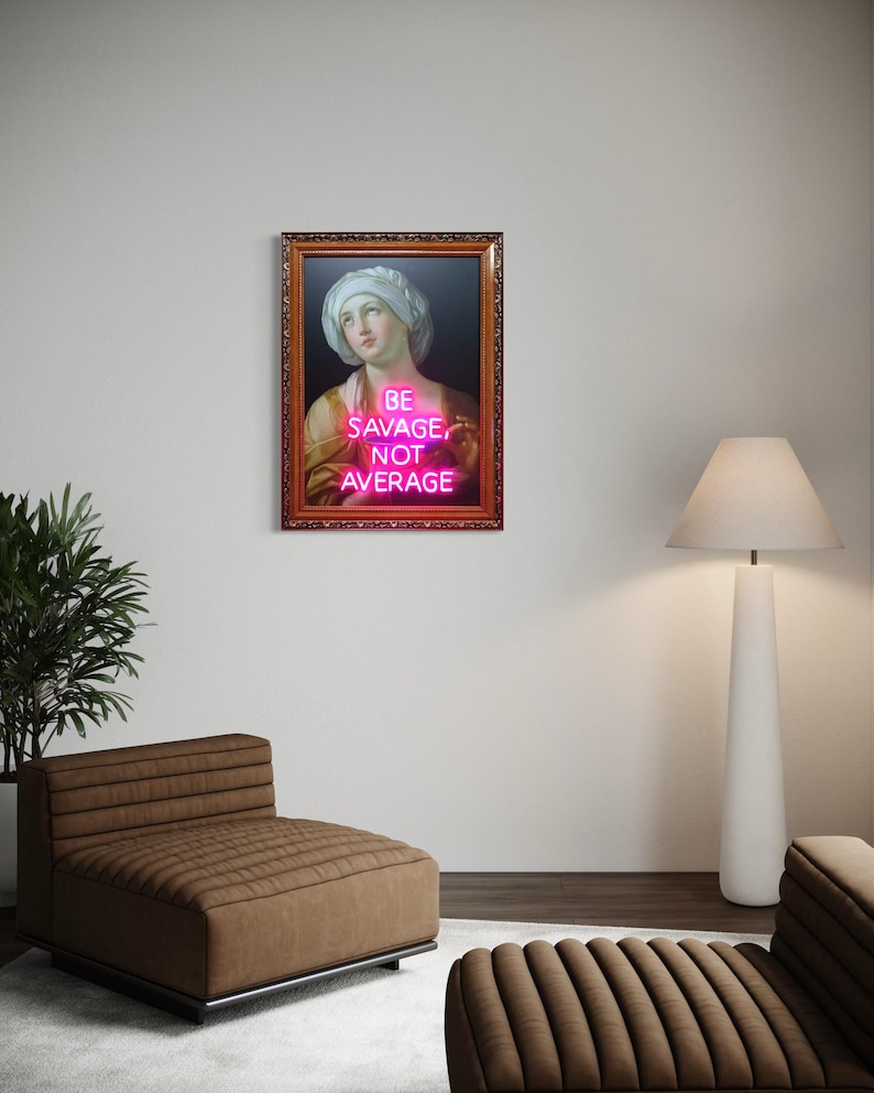 Puede incluir: Una obra de arte enmarcada con un retrato cl&aacute;sico y un letrero de ne&oacute;n rosa. El letrero dice "BE SAVAGE, NOT AVERAGE". La obra de arte est&aacute; en un marco marr&oacute;n adornado, en una pared blanca. La habitaci&oacute;n incluye una silla marr&oacute;n y una l&aacute;mpara de pie blanca.