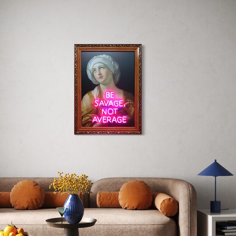 Puede incluir: Una obra de arte enmarcada con un retrato cl&aacute;sico con un letrero de ne&oacute;n rosa que dice "BE SAVAGE, NOT AVERAGE". El retrato es de una mujer que lleva un tocado blanco y una prenda de color dorado. El marco es marr&oacute;n con detalles ornamentados.