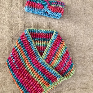May include: A colorful crocheted headband and a matching scarf in shades of pink, green, blue, and orange. The headband is tied in a knot at the top.