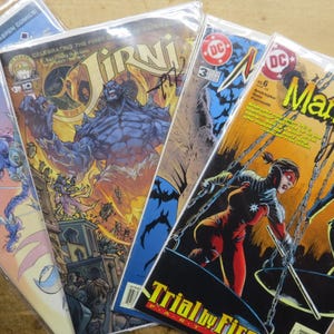 May include: A collection of comic books featuring vibrant illustrations. Titles include "Irni" and "Manhunter," with dynamic artwork and bold colors. The comics are in protective sleeves, showcasing the covers.