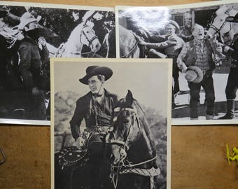 Op de afbeelding: Zwart-wit vintage foto's van cowboys en paarden. Eén afbeelding toont een cowboy te paard, terwijl andere groepen mannen in cowboykleding laten zien. De afbeeldingen zijn gerangschikt op een houten oppervlak.