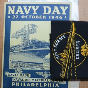 May include: A vintage Navy Day poster from October 27, 1946, featuring a ship illustration, and a black patch with "Navy Science Cruiser" text and a ship design. The poster is blue and white.