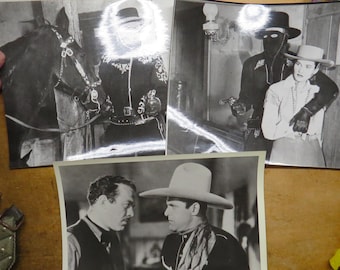 May include: Black and white photographs of Western-themed scenes. One shows a man in a mask holding a gun, another features a man in a cowboy hat, and a third depicts a man with a horse.