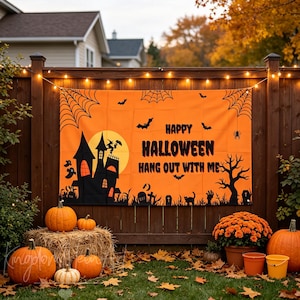 May include: A rectangular orange Halloween banner featuring a black silhouette of a haunted house, a full moon, bats, spiderwebs, and a tree. The text reads HAPPY HALLOWEEN HANG OUT WITH ME in bold black letters. The banner is hung on a wooden fence.