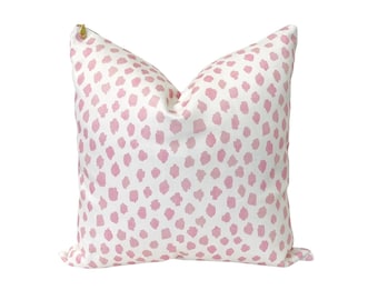 May include: A white pillow with a pink polka dot pattern. The pillow has a zipper closure.