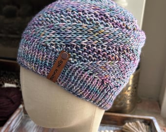 May include: A purple, blue and pink knitted beanie with a brown leather tag that says "Silk Knits".