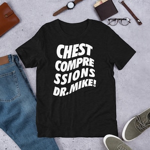 May include: Black t-shirt with white text that reads "CHEST COMPRESSIONS DR. MIKE!"