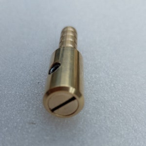 May include: A brass fitting with a threaded end and a slot for a screwdriver. The fitting is designed to connect two pieces of pipe or tubing.