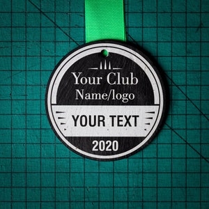 May include: Black and white round tag with the text "Your Club Name/logo" and "YOUR TEXT" with the year 2020 below the text. The tag is hanging from a green ribbon.